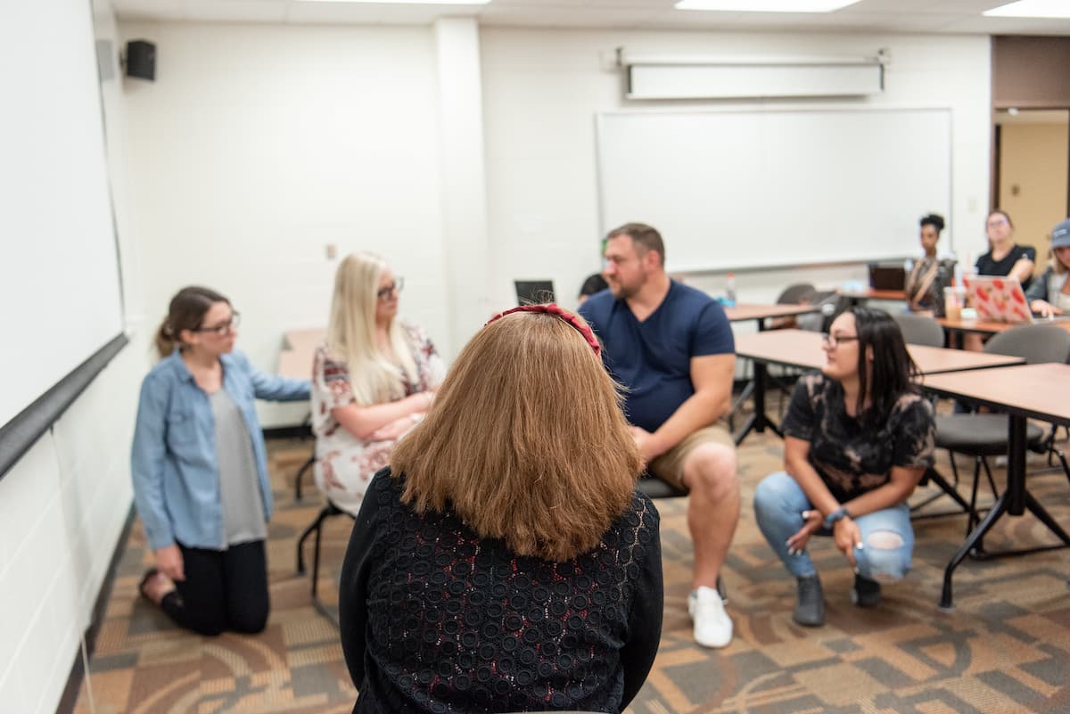 classroom with students sitting in a circle on the floor engaged in discussion