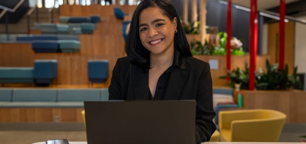 Flerida V. smiles while working on her laptop.