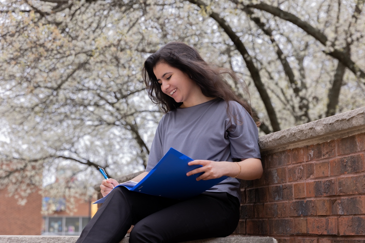 A student smiles while writing in their folder.