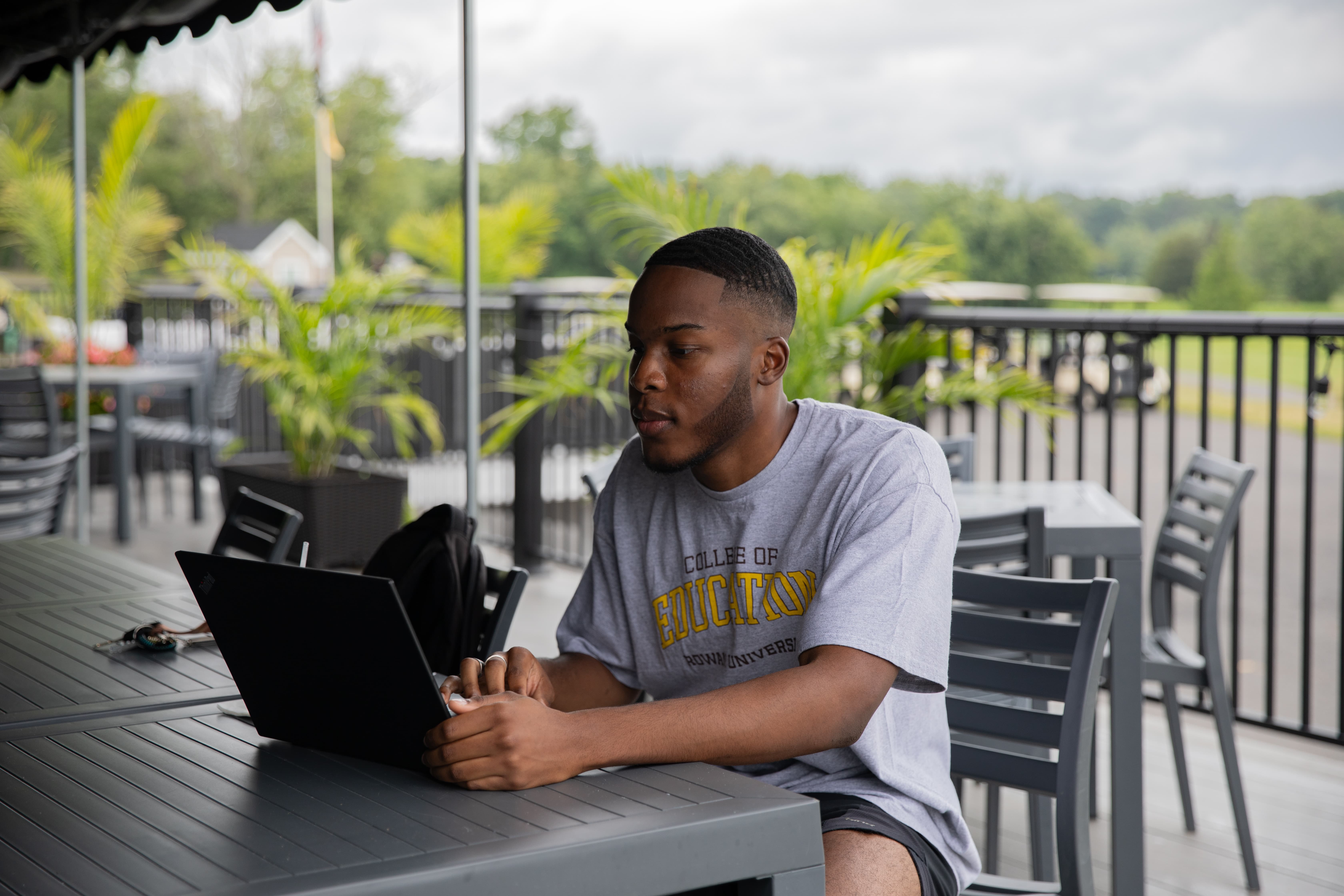 A student sits at a table and works on their laptop.