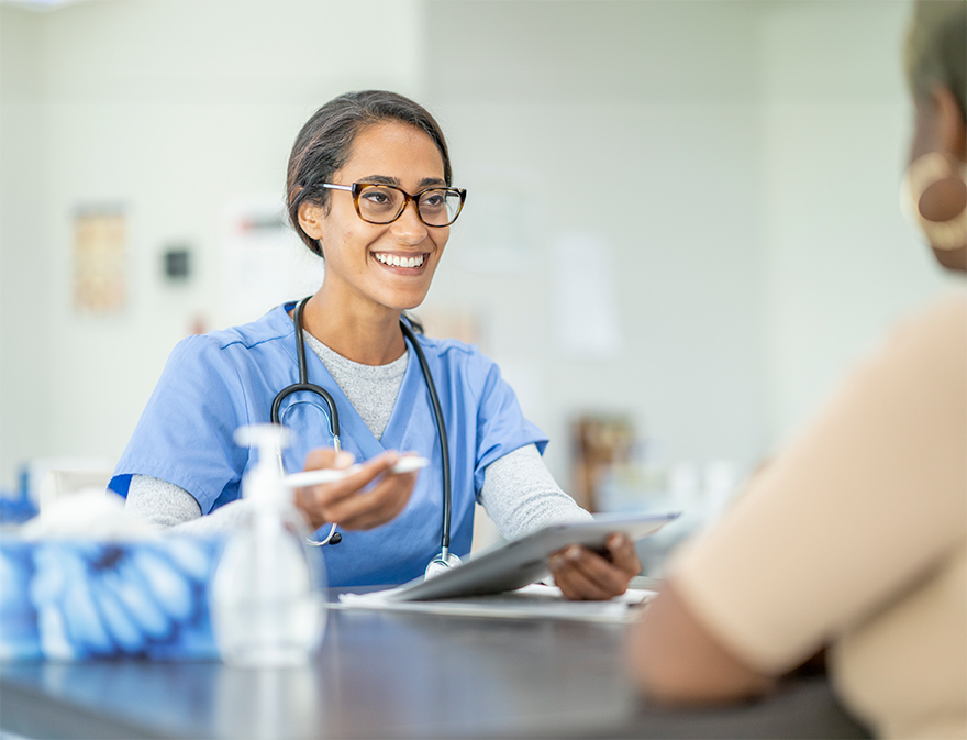 A healthcare professional smiles while sitting across from a patient.