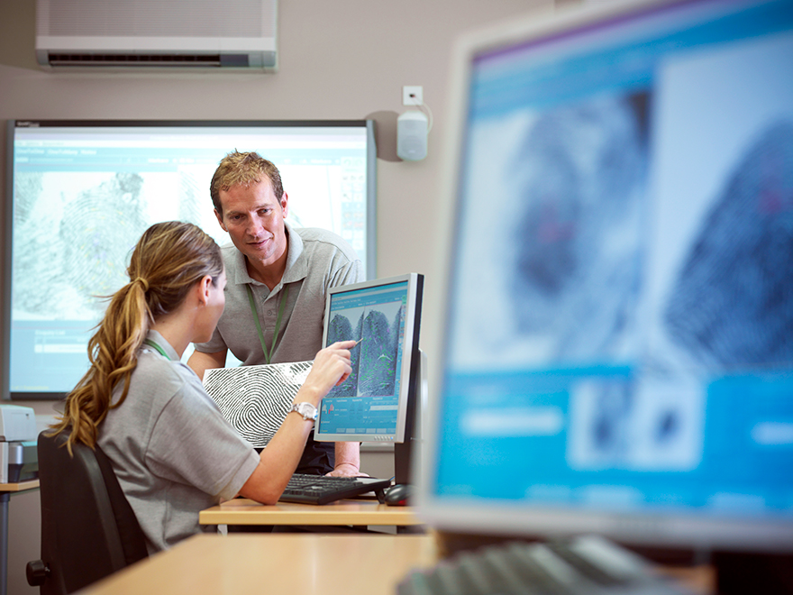A student speaks with their instructor at a computer.