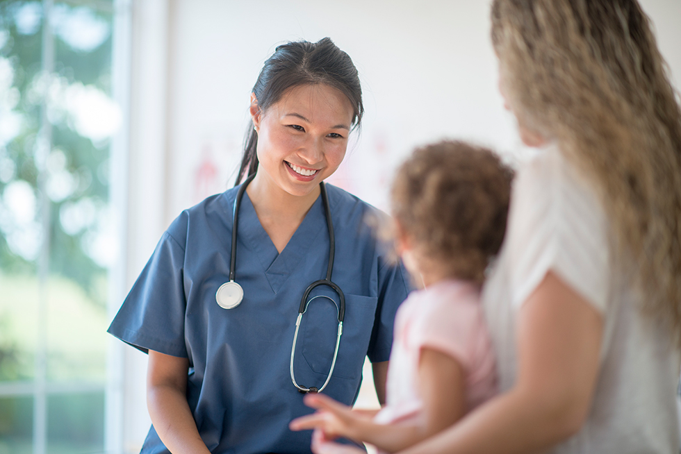 A healthcare professional smiles while speaking with patients.