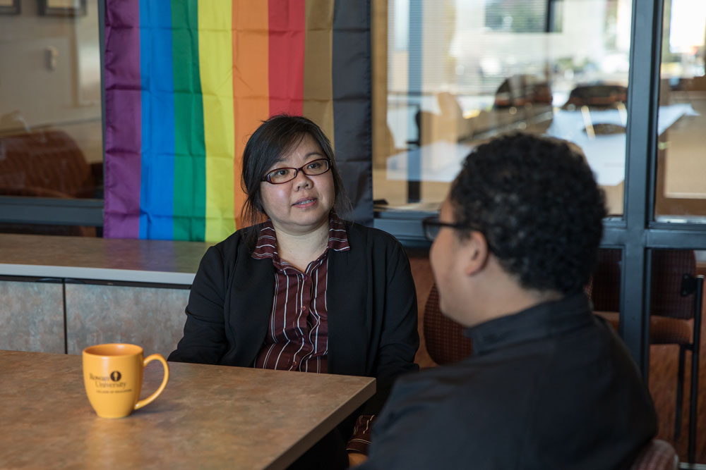 Two individauls sit and talk at a table.
