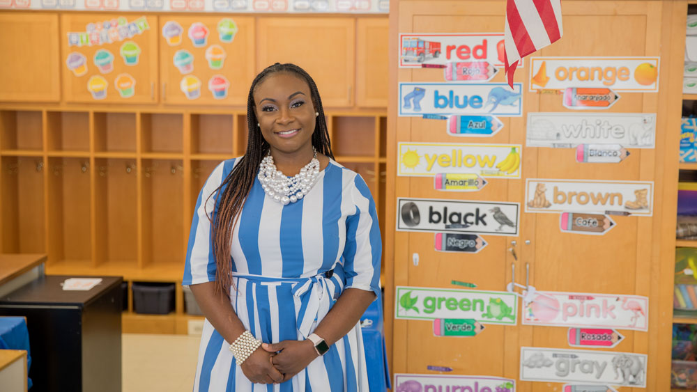 An educator poses for a photo in their classroom.