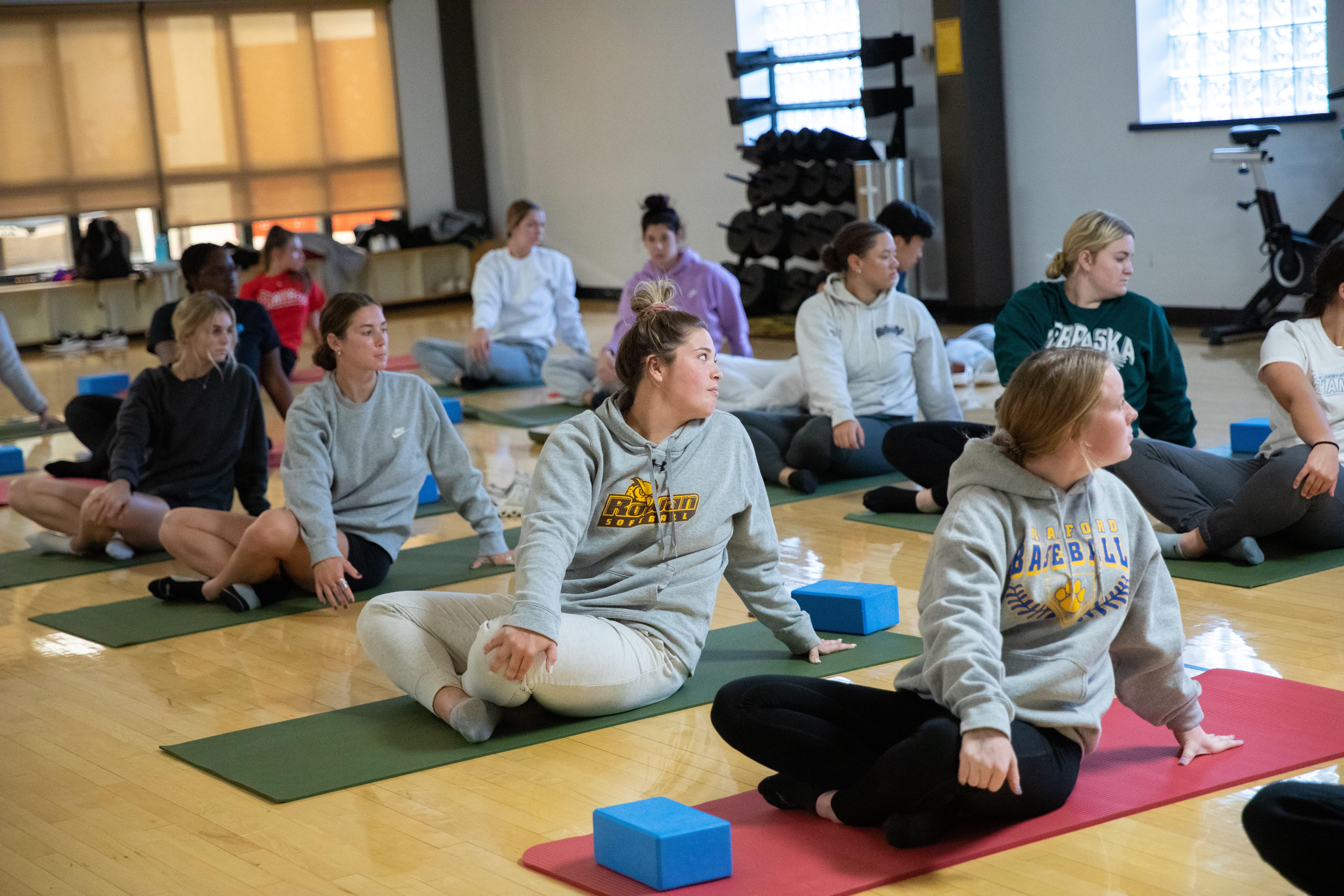 A group of Rowan students sit on yoga mats during a yoga class.