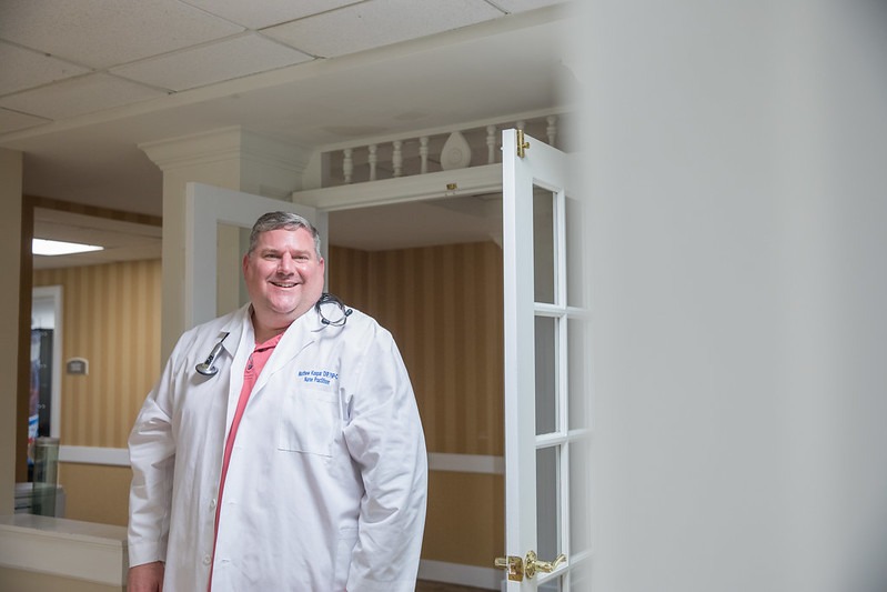 A man stands in a white coat in the hallway.