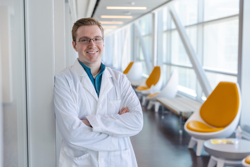A student smiles with a white coat on.