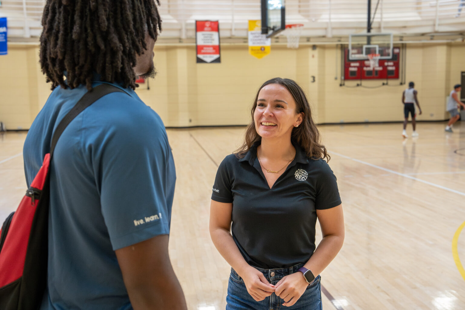 Christina F. smiles while speaking to someone in a gym on Rowan's main campus in Glassboro, NJ.