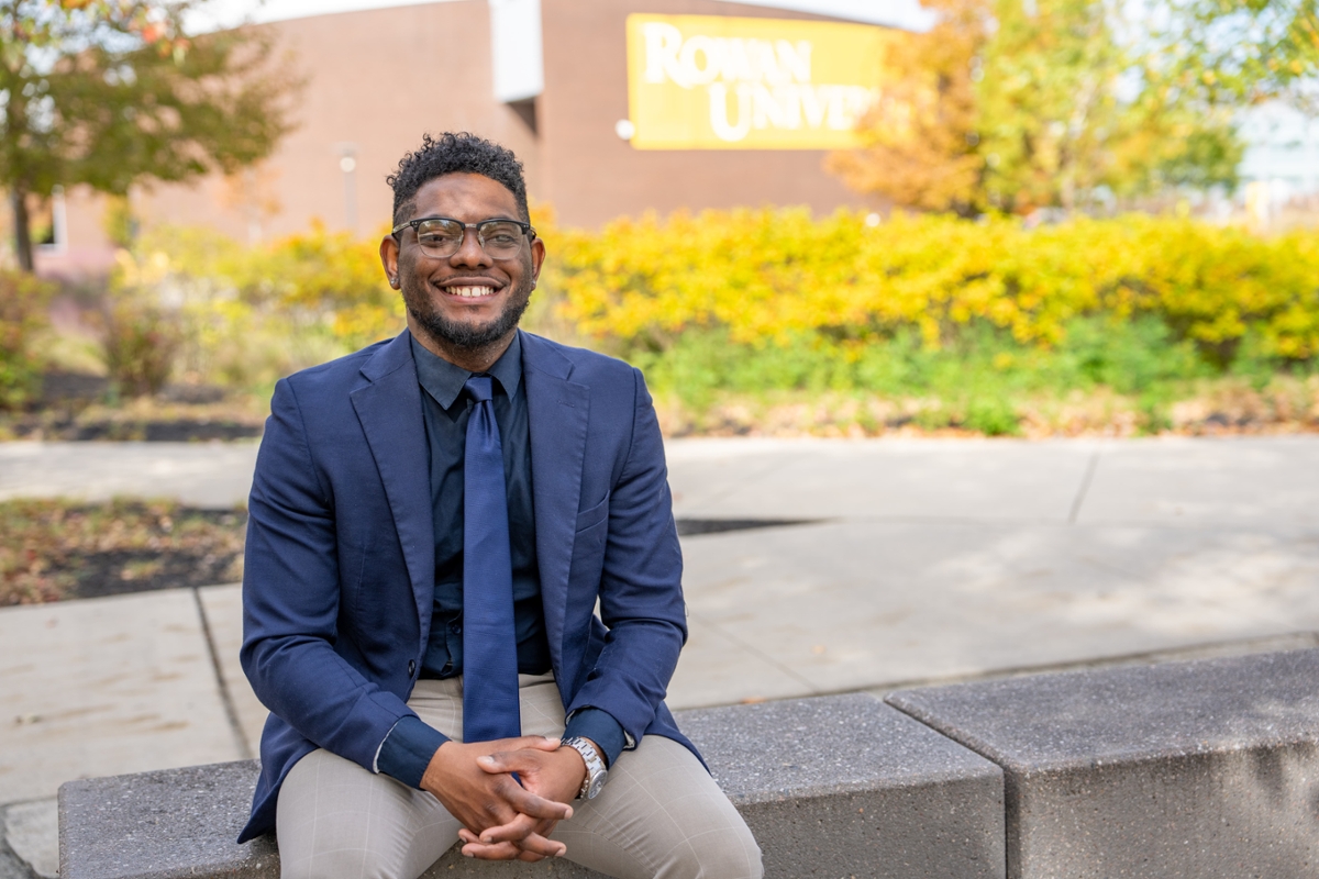 Shawn B. smiles while sitting on Rowan's main campus in Glassboro, NJ.