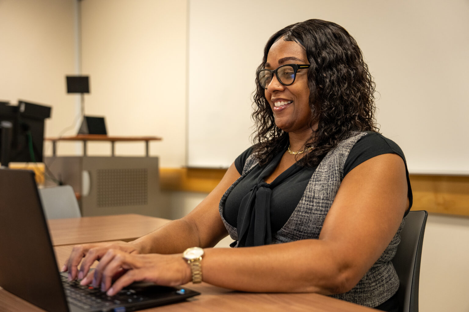 Tajauna S. smiles while working on her laptop.