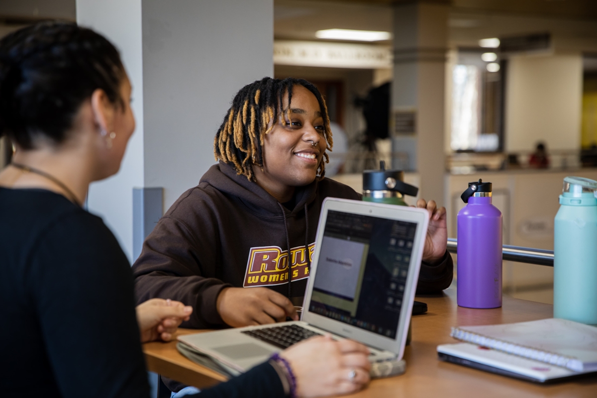 Rowan students sit and work on their laptops at a table in the library on Rowan's main campus in Glassboro, NJ.